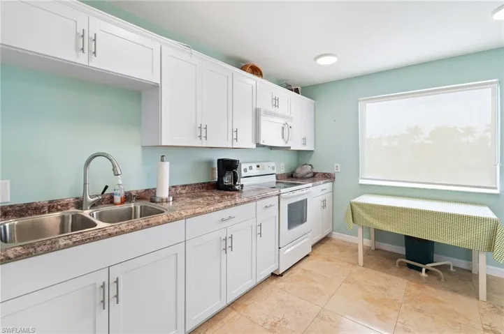 Clubhouse Kitchen with sink, white appliances, and white cabinets