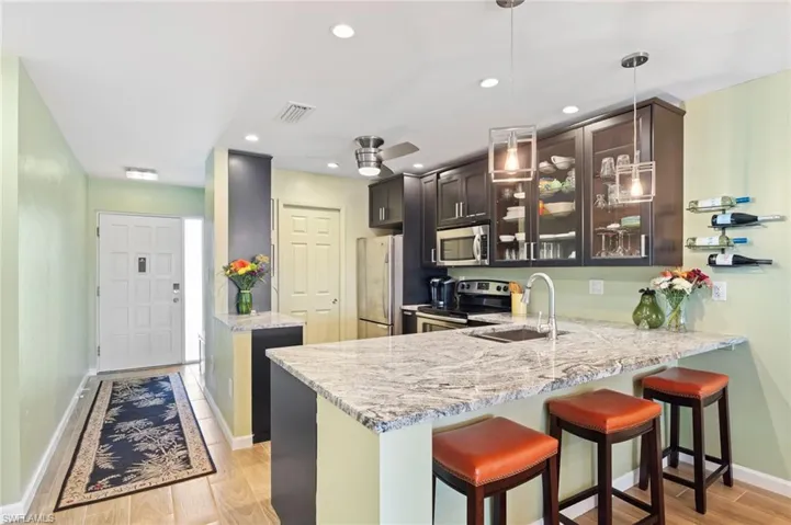 Kitchen with stainless steel appliances, kitchen peninsula, light wood-type flooring, and dark brown cabinets