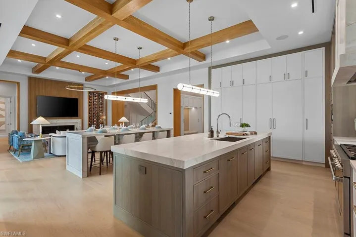 Kitchen featuring a sink, a spacious island, light wood-style floors, double oven range, and coffered ceiling