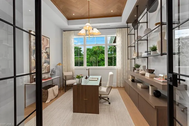 Office featuring wood finished floors, a tray ceiling, baseboards, and a chandelier