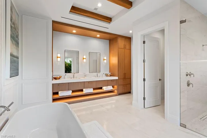 Bathroom with double vanity, marble look tiles, a marble finish shower, a freestanding tub, and recessed lighting