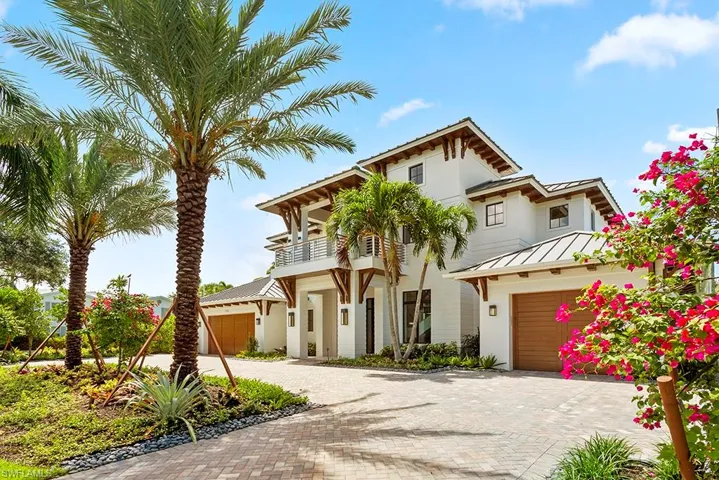 View of front of home featuring a balcony, decorative driveway, stucco siding, a standing seam roof, and metal roof