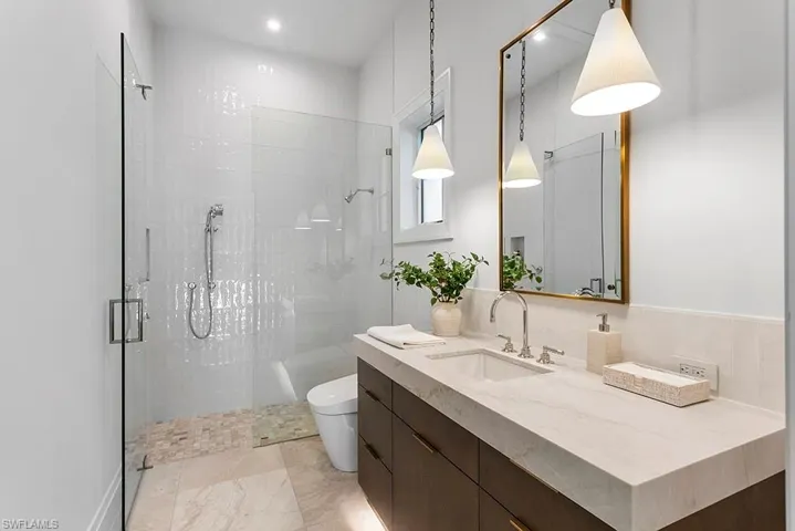 Bathroom featuring a shower stall, toilet, and vanity