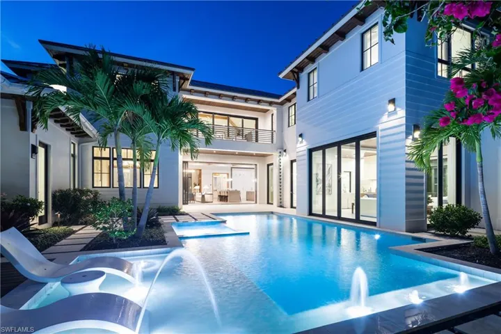 Back of property featuring a pool with connected hot tub and a balcony