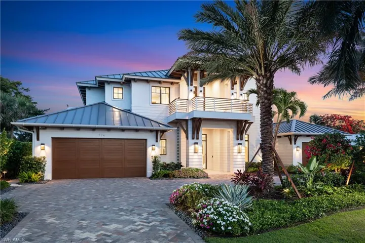 View of front facade featuring a standing seam roof, a balcony, an attached garage, a metal roof, and decorative driveway