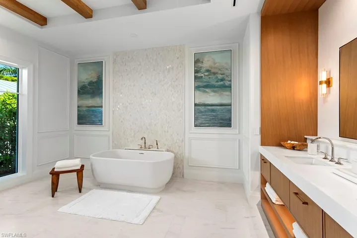 Bathroom with a decorative wall, vanity, a freestanding tub, and beam ceiling