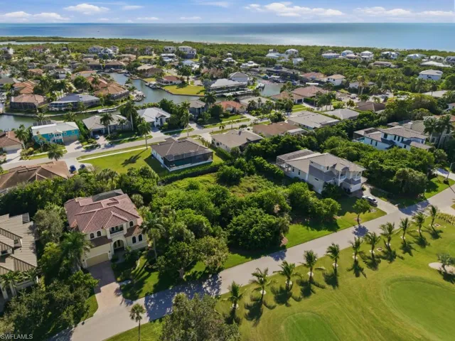 Aerial perspective featuring coastal proximity, golf course frontage, and surrounding mature vegetation