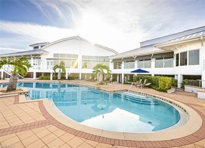 Inground swimming pool with integrated stair entry, expansive paved patio, and metal roof structure
