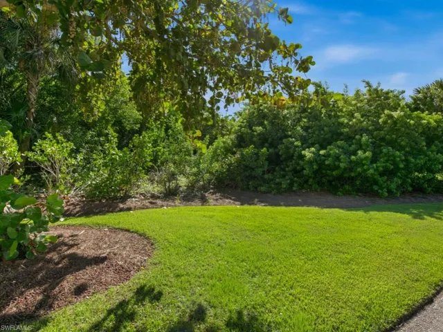 Expansive lot featuring manicured grass, organic mulched landscape beds, and mature indigenous vegetation