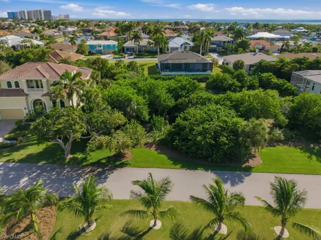Expansive residential lot featuring mature trees, manicured landscaping, and coastal proximity
