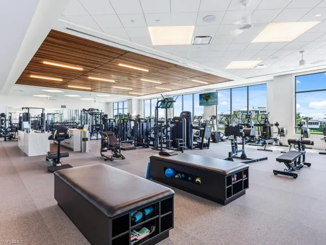 Fitness center featuring floor-to-ceiling windows, linear wood-slat ceiling detailing, integrated recessed lighting, and industrial-grade rubber flooring