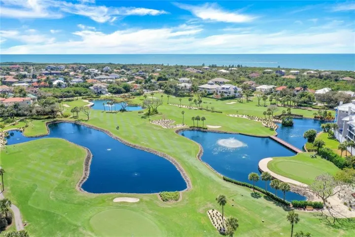 Golf course landscape featuring multiple water hazards, aerating fountains, expansive green space, and palm trees