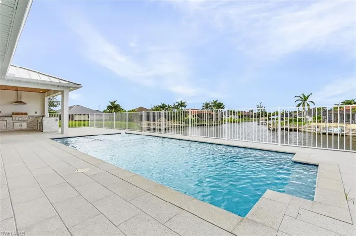 View of swimming pool with a grill, a water view, exterior kitchen, and a patio area