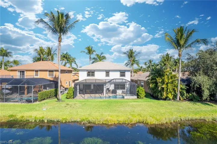 Back of house with a lanai, a pool, and a lawn