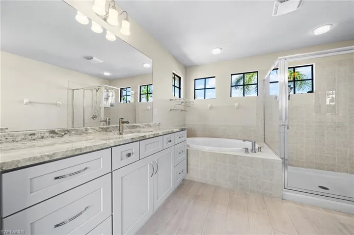 Full bath featuring a stall shower, vanity, and a garden tub