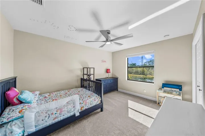 Carpeted bedroom with ceiling fan and a desk