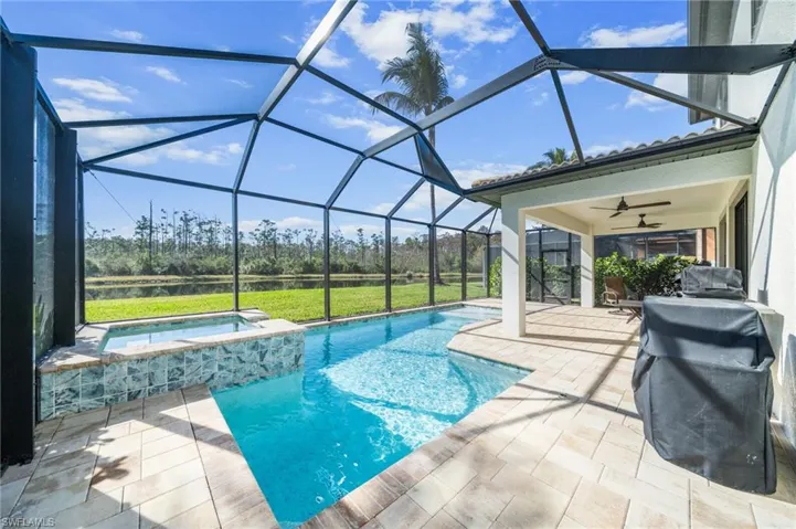 View of pool with a sunroom, grilling area, a patio area, a pool with connected hot tub, and a lanai