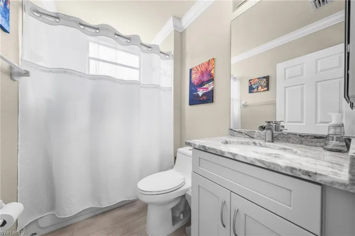 Bathroom with vanity, crown molding, and light wood finished floors