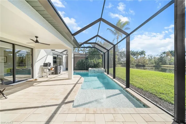 Unfurnished sunroom with a patio, ceiling fan, a water view, a jacuzzi, and vaulted ceiling