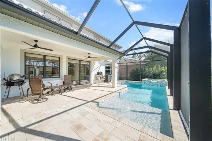 View of swimming pool featuring a sunroom, a pool with connected hot tub, a patio area, grilling area, and a lanai