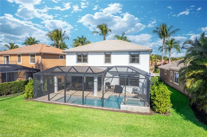 Rear view of house featuring a lanai, a tiled roof, and a lawn