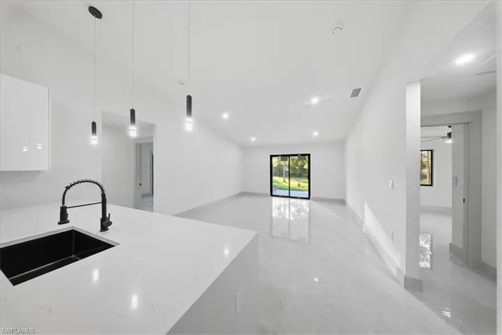 Kitchen featuring light stone counters, pendant lighting, white cabinets, modern cabinets, and open floor plan