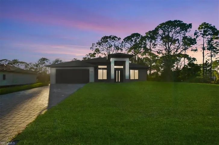 View of front facade featuring a yard, decorative driveway, a garage, and stucco siding