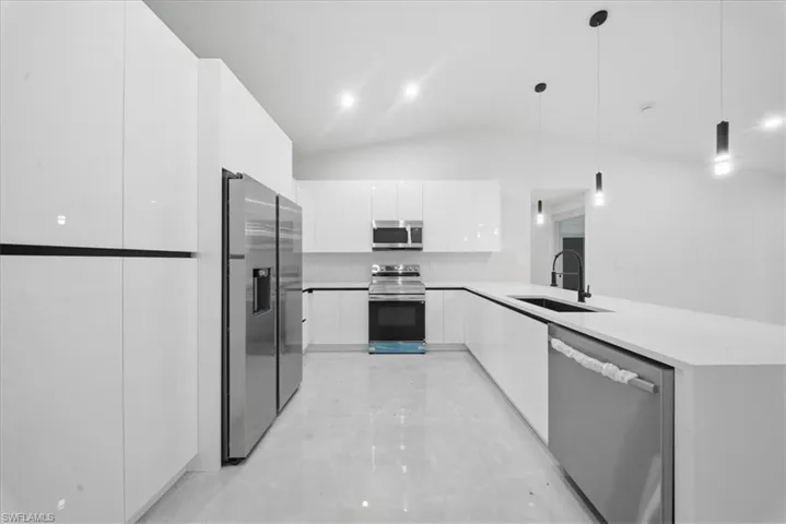 Kitchen with stainless steel appliances, white cabinets, a peninsula, pendant lighting, and modern cabinets