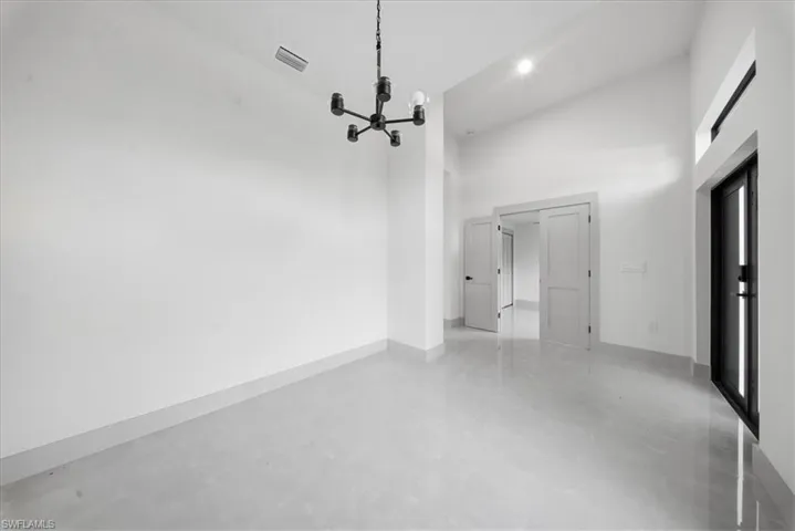 Unfurnished dining area with a high ceiling, a chandelier, and concrete floors