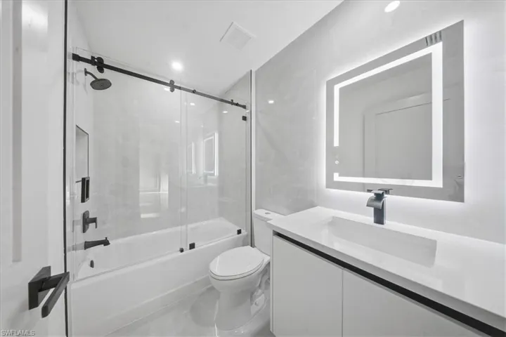 Full bath featuring vanity and bath / shower combo with glass door