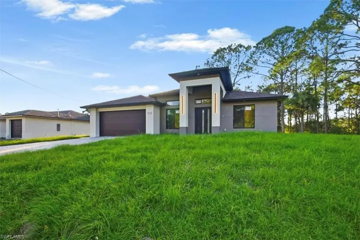 View of front of house with a garage, driveway, and stucco siding