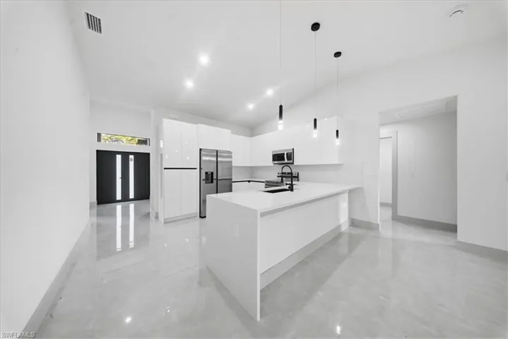 Kitchen featuring a peninsula, stainless steel appliances, white cabinetry, modern cabinets, and decorative light fixtures