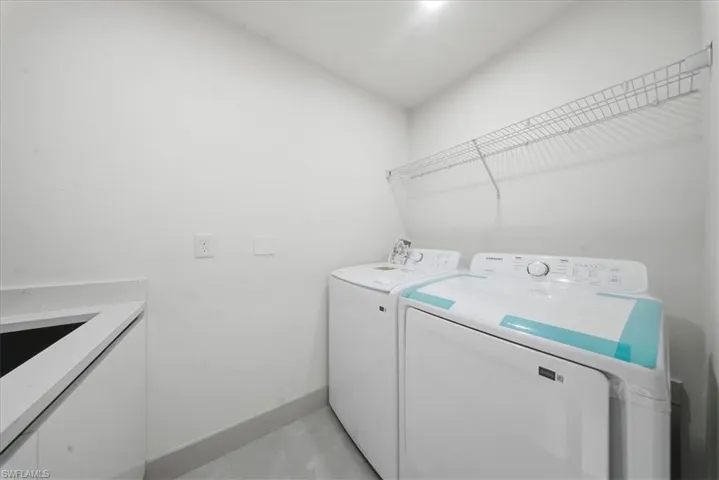 Laundry room with baseboards and washer and clothes dryer