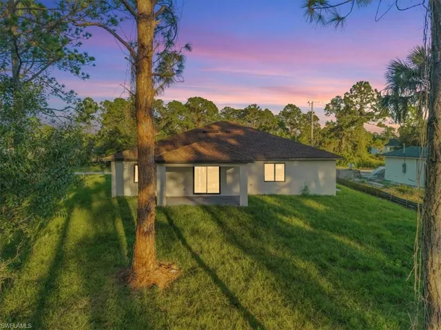 Rear view of house featuring a patio, stucco siding, and view of scattered trees