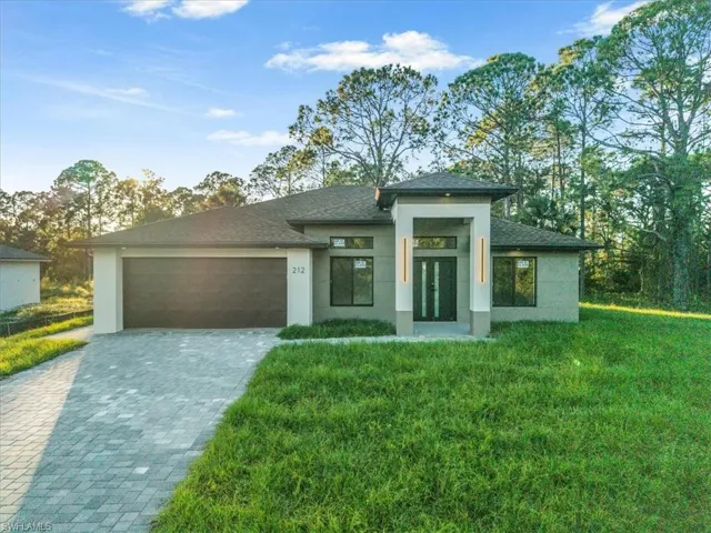 Prairie-style house with an attached garage, decorative driveway, stucco siding, and a front yard