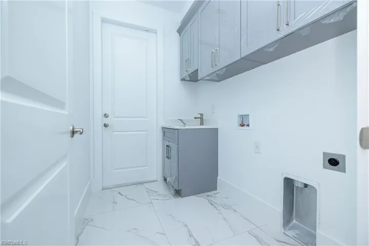 Laundry room featuring light marble finish flooring, washer hookup, electric dryer hookup, and cabinet space