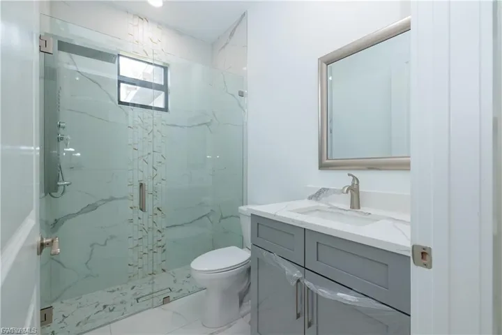 Bathroom featuring vanity, a marble finish shower, and marble finish flooring