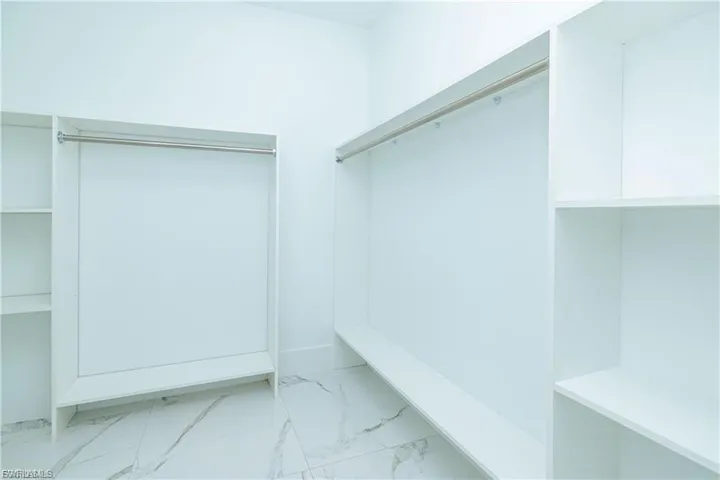 Spacious closet featuring light marble finish floors