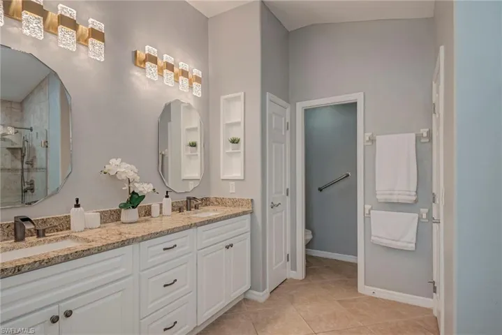 Bathroom featuring double vanity, a stall shower, and light tile patterned flooring