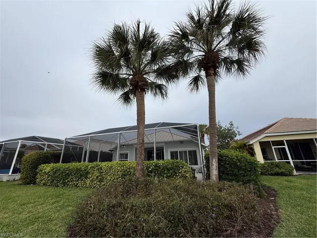 Rear view of property with a sunroom, a lawn, and glass enclosure