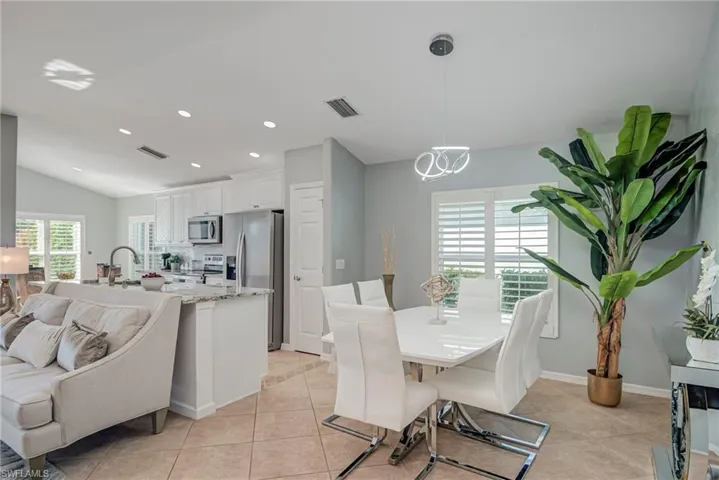 Dining room with lofted ceiling, light tile patterned flooring, and recessed lighting