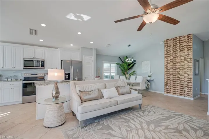 Living area with light tile patterned floors, ceiling fan, lofted ceiling, and recessed lighting