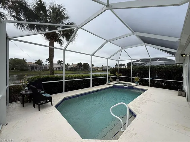 Combined pool / hot tub featuring a sunroom, a patio area, a residential view, and glass enclosure