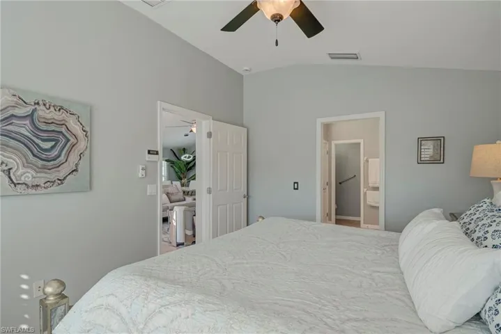 Bedroom with lofted ceiling, a ceiling fan, and ensuite bath