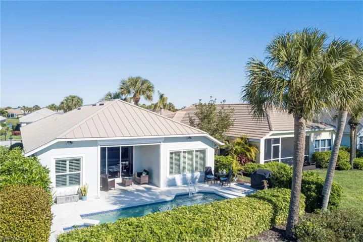 Back of property with a patio, a standing seam roof, a metal roof, stucco siding, and an outdoor pool