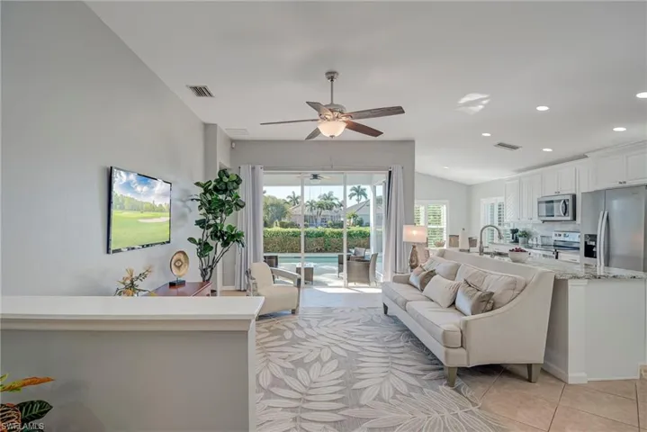 Living room featuring light tile patterned floors, a ceiling fan, recessed lighting, and lofted ceiling