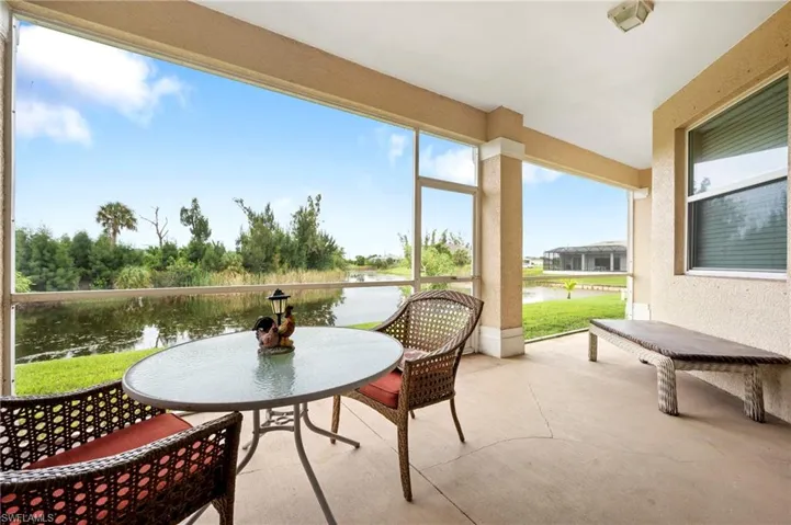 Sunroom with a water view, a textured wall, and concrete floors