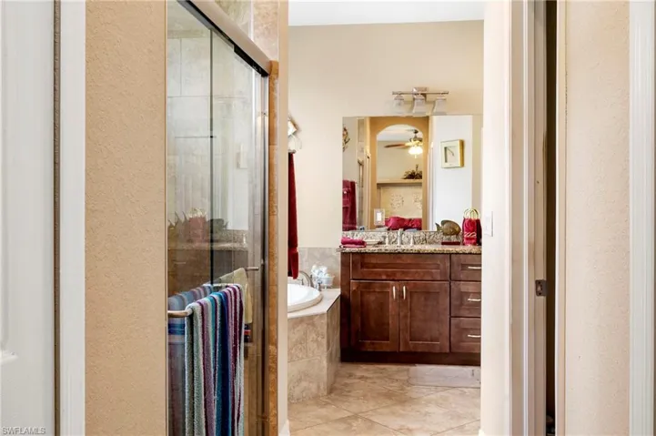 Full bath with vanity, a stall shower, a garden tub, ceiling fan, and light tile patterned flooring