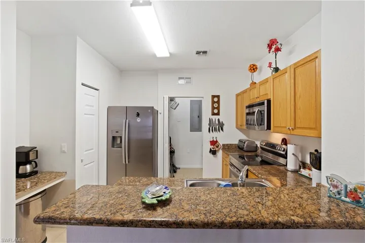 Kitchen featuring stainless steel appliances, electric panel, a peninsula, and tile patterned floors