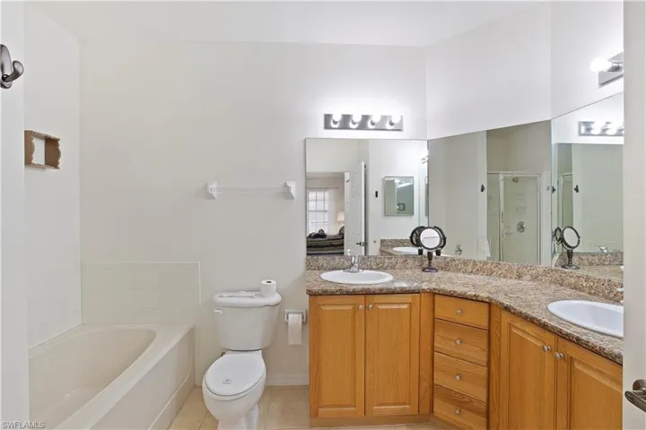 Bathroom featuring a shower stall, double vanity, a garden tub, and tile patterned flooring